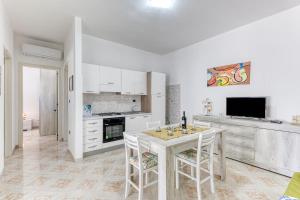 a kitchen with white cabinets and a table and chairs at Salentoandmore - Smeralda Onda Blu in Marina di Pescoluse