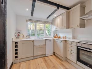 a kitchen with white cabinets and a window at Darla Cottage in Thornton Dale