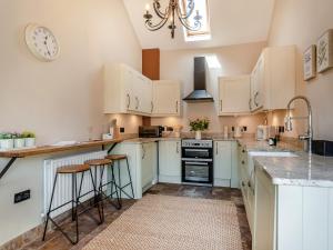 una cucina con armadi bianchi e un orologio sul muro di The Old Moat Barn a Elton Altre 11 foto