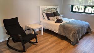 a bedroom with a bed and a black chair at Loft anexo en chalet, con piscina de uso privado in San Juan +3 photos
