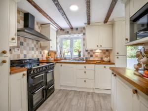a kitchen with white cabinets and a stove at Miners Arms Cottage in Stepaside