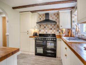 a kitchen with a black stove and white cabinets at Miners Arms Cottage in Stepaside