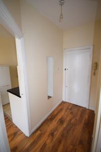 an empty room with a white door and wooden floors at Cosy 1 Bedroom Flat in Peckham in London