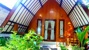 a wooden house with a porch and some plants at Ina Gili Guesthouse in Gili Islands