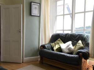 a black leather couch sitting in front of a window at Scenery Cottage in Bridford