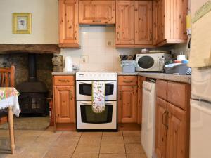 a kitchen with wooden cabinets and a white stove top oven at Scenery Cottage in Bridford