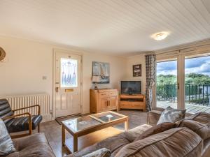 a living room with a couch and a tv at Sunset Lodge in Brundall
