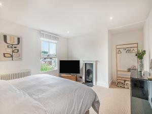 een witte slaapkamer met een bed en een televisie bij Lavender Cottage in Coltishall +8 foto's