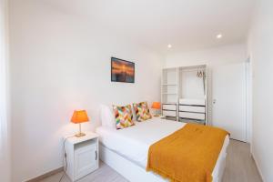 een witte slaapkamer met een bed en een lamp op een nachtkastje bij VIVA Elias Sunset Apartment Gaia in Vila Nova de Gaia
