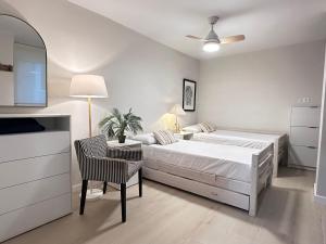 a white bedroom with a bed and a table and chair at EcoCasa 12PAX perfecta grupos, reforma lujo, junto parada Burjassot metrovalencia, cerca centro Valencia y playa, lavadora, secadora equipamiento total in Burjasot