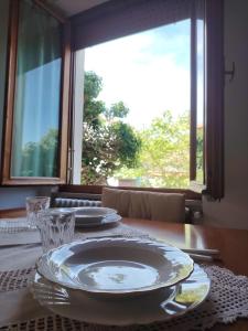 einen Tisch mit Tellern und Gläsern auf einem Tisch mit Fenster in der Unterkunft Casa di Caterina in Castiglioncello