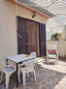 eine Terrasse mit einem Tisch, Stühlen und einer Tür in der Unterkunft Casa di Caterina in Castiglioncello
