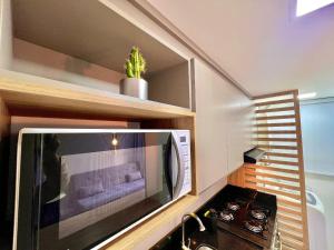 a microwave in a kitchen with a plant on a shelf at Urban Apt 601 Comfortable and Complete in Caxias do Sul