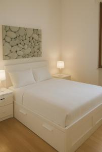 a white bed in a bedroom with two lamps at Casa Sofia in Villasimius