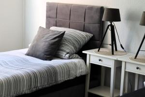 Una cama con cabecero gris junto a una mesa con lámparas. en I&D Apartments, en Duisburg