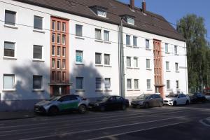 una fila de autos estacionados frente a un edificio blanco en I&D Apartments, en Duisburg