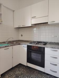 eine Küche mit weißen Schränken und einem schwarzen Backofen in der Unterkunft Casa di Caterina in Castiglioncello