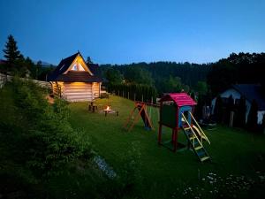 a yard with a cabin and a playground at Malowany Domek w Górach in Ciche