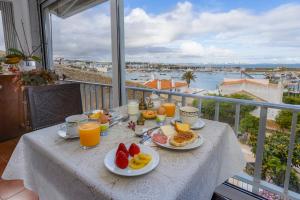 a table with breakfast food and orange juice on a balcony at Casa Flor do Mar Lagos in Lagos