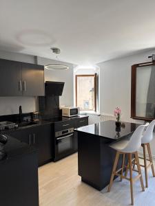a kitchen with black cabinets and a table and chairs at Le temple, moderne et élégant Cœur de Limoges in Limoges