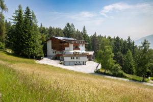 dom na zboczu wzgórza z drzewami w obiekcie Hotel Pension Tyrol w mieście Seefeld in Tirol