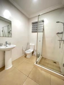 a bathroom with a toilet and a sink and a shower at Sunny's Place Luxury Apartments in Accra