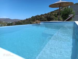 a swimming pool with an umbrella and a swimming pool at Celini villa Tinos in Krokos