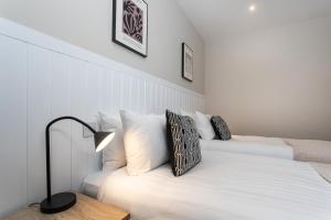 Dormitorio blanco con cama con almohadas blancas en Mode Pleasure Beach Apartments, en Blackpool