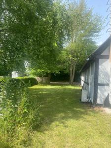 a yard next to a house with a tree at Charmerende feriehus tæt på Knuthenborg in Maribo