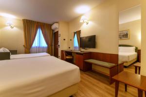 a hotel room with two beds and a desk at Hotel Falco D'Oro by Falco D'Oro Hotels in Tolè