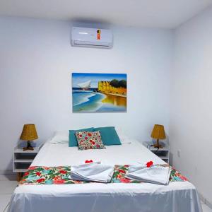 a bedroom with a bed with a painting on the wall at Pousada Ello in São Miguel do Gostoso