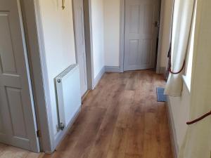 einen leeren Flur mit einem Heizkörper und Holzböden in der Unterkunft Fitling Cottage in Garton