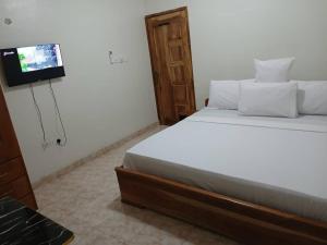 a bedroom with a bed with a tv on the wall at Madora Lodge in Tafi Atome