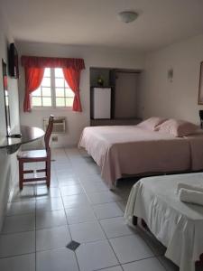 una camera da letto con due letti, un tavolo e una finestra di Viver Hotel Fazenda a Moreno