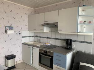 グランカン・メジーにあるAppartement front de merの白いキャビネットとコンロ付きオーブンを備えたキッチン