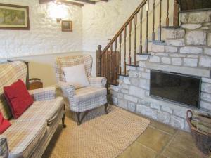 a living room with two chairs and a stone fireplace at Oxlow End Cottage in Peak Forest