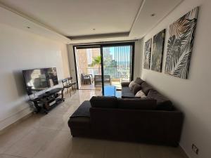 a living room with a couch and a flat screen tv at Prestigia plage des nations in Sale