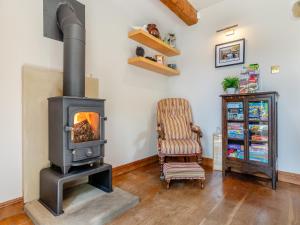a wood stove in a living room with a chair at Perkins Cottage in Ashover