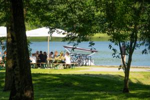 un gruppo di persone seduti ai tavoli vicino all'acqua di Saulės laikrodžio apartamentai a Šiauliai