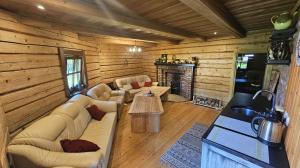 a living room with couches and a fireplace in a log cabin at Ziedu pirts in Auciems