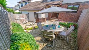 a patio with a table with an umbrella and chairs at Cockleshell Croyde Sleeps 4 By the Seaside in Croyde