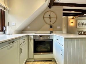 a kitchen with white cabinets and a clock on the wall at 1 Bed in Exmoor National Park 89766 in Parracombe +7 photos