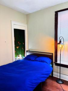 une chambre avec un lit avec des draps bleus et une fenêtre dans l'établissement Nintendo, Filtered H2O, Cafe, Central, Self-Check, à Troy 24 autres photos