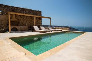 a swimming pool with lounge chairs and a fireplace at Villa Fragkaki in Oitylo