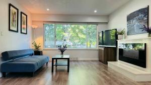 a living room with a blue couch and a flat screen tv at Cozoro 3 BEDROOMS Centre Vancouver in Vancouver