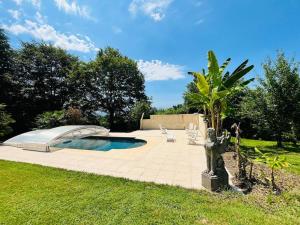 einen Garten mit einem Pool und einer Palme in der Unterkunft La Roquetière, Domaine Paradisiaque pour 12 personnes in Ledeuix