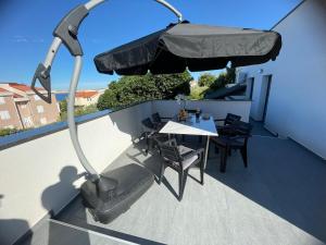 a table and chairs on a balcony with an umbrella at Second home apartment - rose gold in Kustići