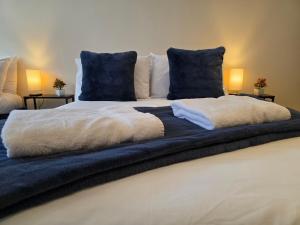 a bed with white blankets and blue pillows on it at Modern Apartment 8 in Town Centre in Ipswich