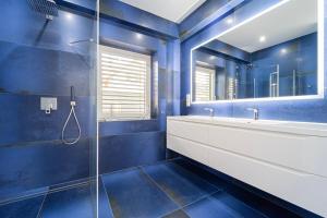 a blue bathroom with a sink and a mirror at Keszeg Villa Zamárdi in Zamárdi
