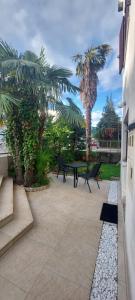Un patio con mesa y sillas y palmeras. en Rose Apartments, en Ičići